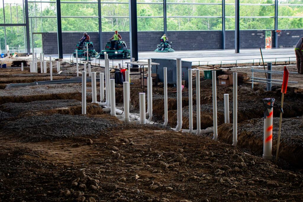 Plumbing pipes dug out with men on flooring machines