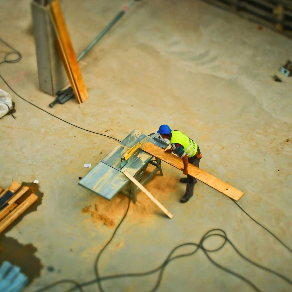 Man wearing safety grear using table saw to cut piece of wood