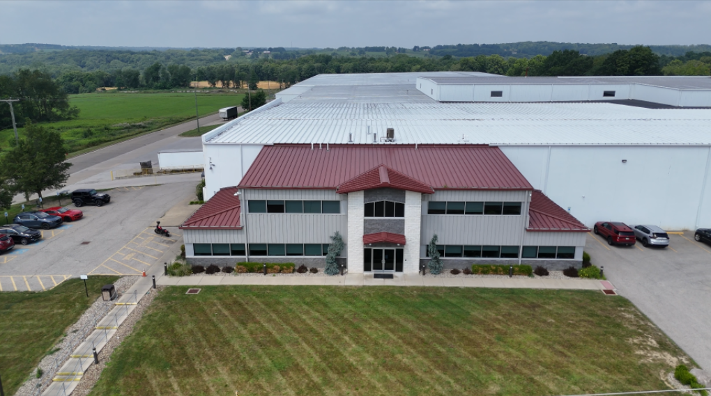 Industrial warehouse with red roof, windows, and grass plot