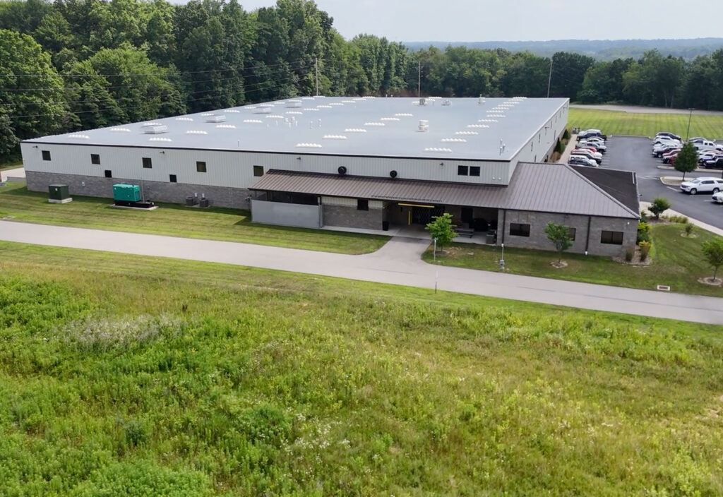 Warehouse with lots of windows, double doors, parking lot with cars